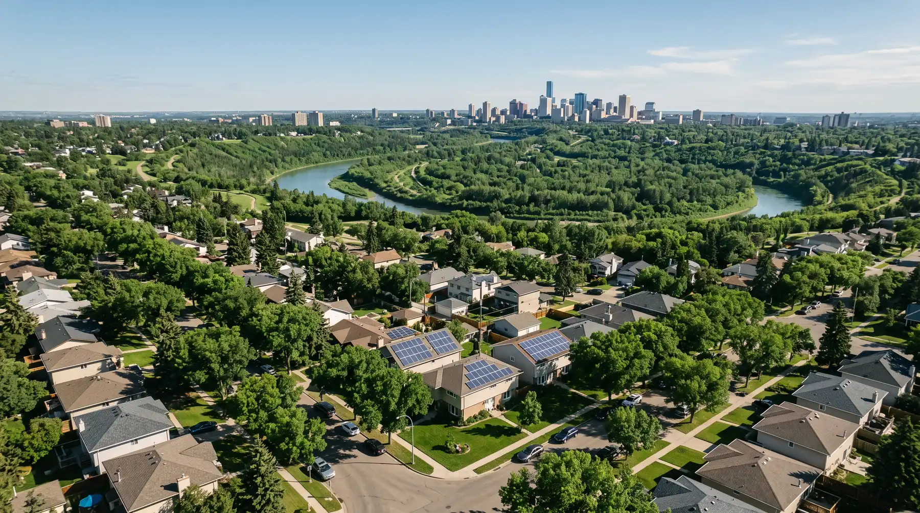 Aerial view of a leafy Edmonton neighbourhood with rooftop solar and the river valley and downtown beyond